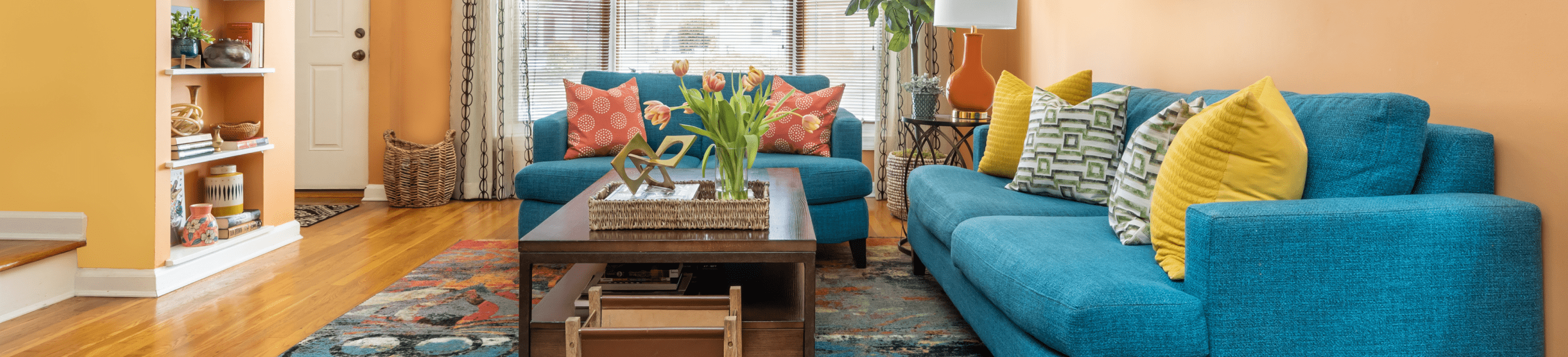 Living Room with orange walls, wooden floors, and blue-green couch