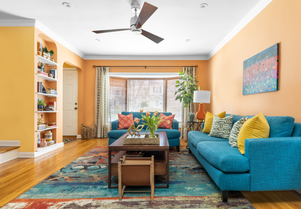 Living Room with orange walls, wooden floors, and blue-green couch