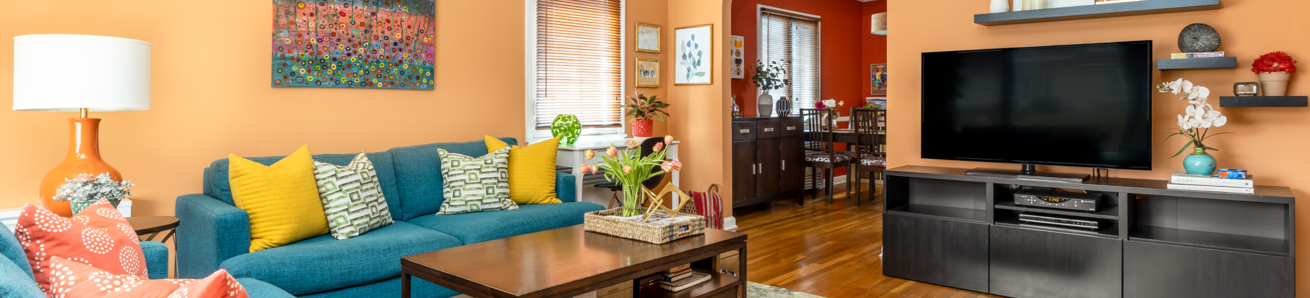 Living Room with orange walls, wooden floors, and blue-green couch